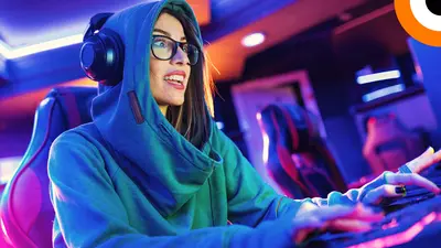 Une jeune femme portant un casque sourit face à son ordinateur. 