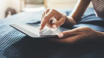 Une personne posée sur son lit navigue sur sa tablette