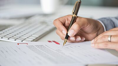 Close-up of hands holding a pen at a table