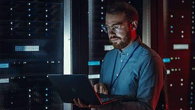 Un homme regarde un ordinateur dans un data center sombre