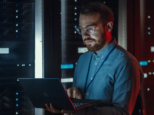Un homme regarde un ordinateur dans un data center sombre