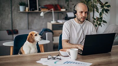 Afbeelding man met hond achter laptop