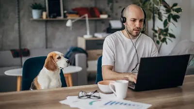 Afbeelding man met hond achter laptop