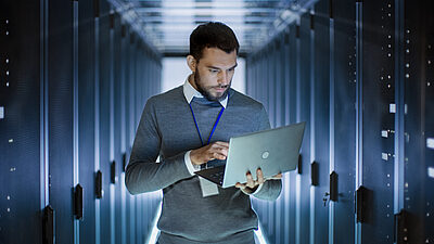 Un homme dans un data center consulte son ordinateur portable