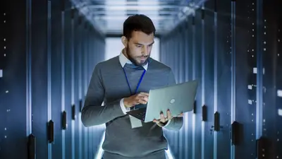 Un homme dans un data center consulte son ordinateur portable