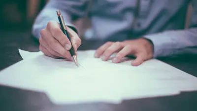 Gros plan sur la main d'une personne qui écrit sur un document papier