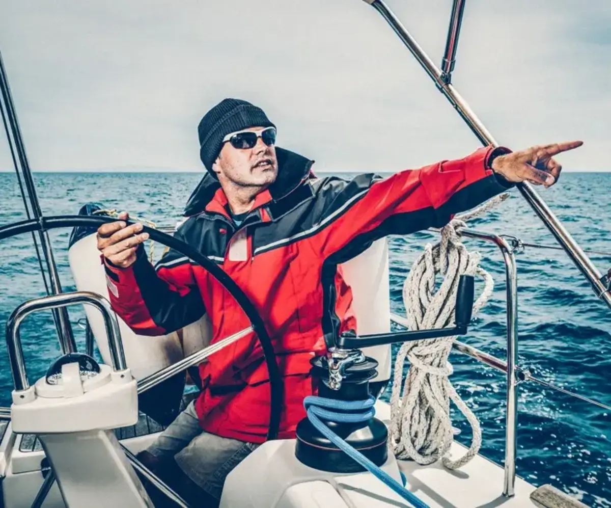 Un navigateur sur un bateau pointe du doigt vers l'horizon