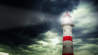 A lighthouse standing against a dark, stormy sky, symbolizing guidance and safety amid chaos.