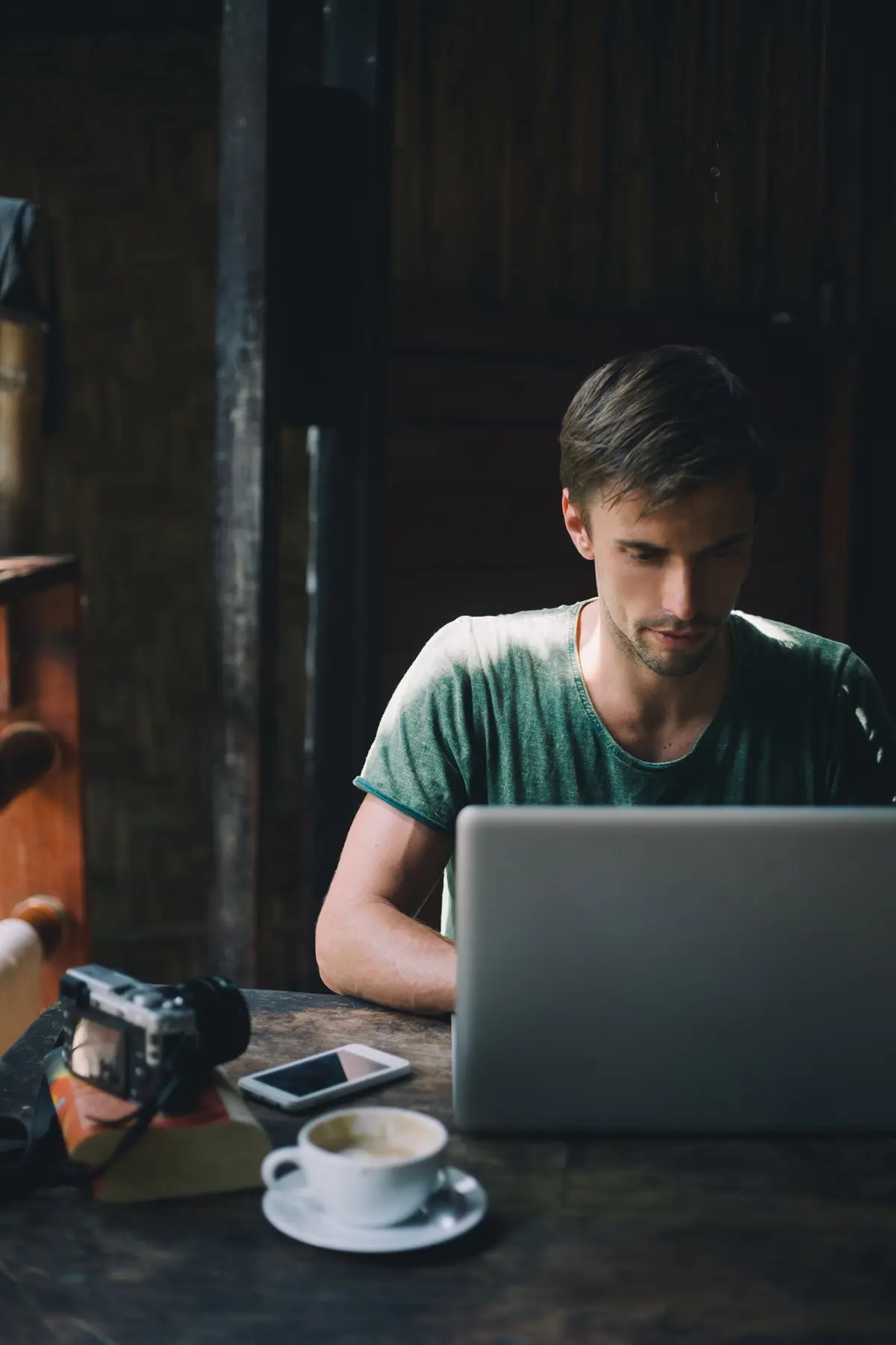 un homme assis dans un café tape sur son ordinateur portable