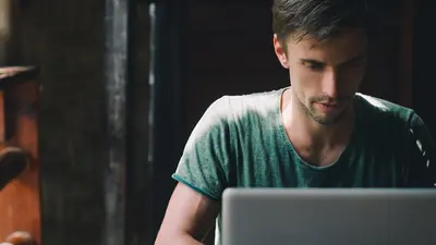un homme assis dans un café tape sur son ordinateur portable