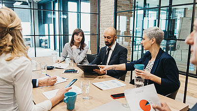 Business people around a table discussion figures