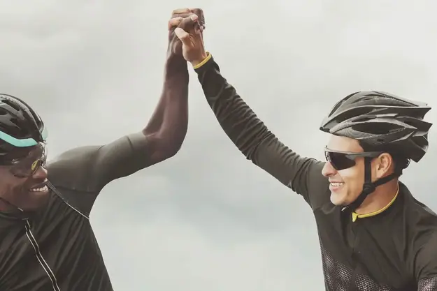 Two people on bicycles giving a high five