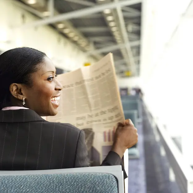 Smiling businesswoman reading a newspaper while travelling
