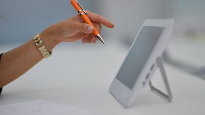 main devant un écran de tablette