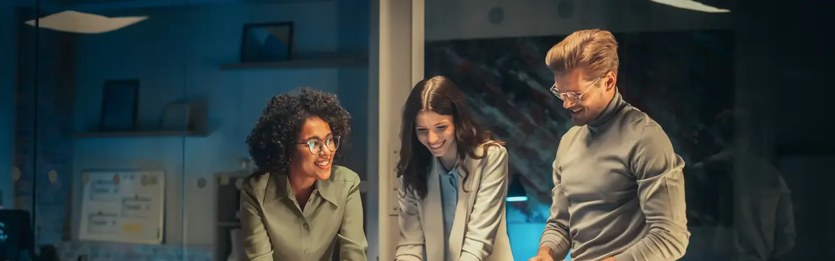 Three coworkers standing in front of a monitor