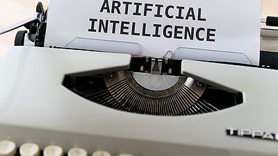 Une machine à écrire avec une feuille sur laquelle on peut lire les mots "Intelligence artificielle" en Anglais. 