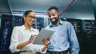 Un homme et une femme qui regardent une tablette dans un centre de donnée