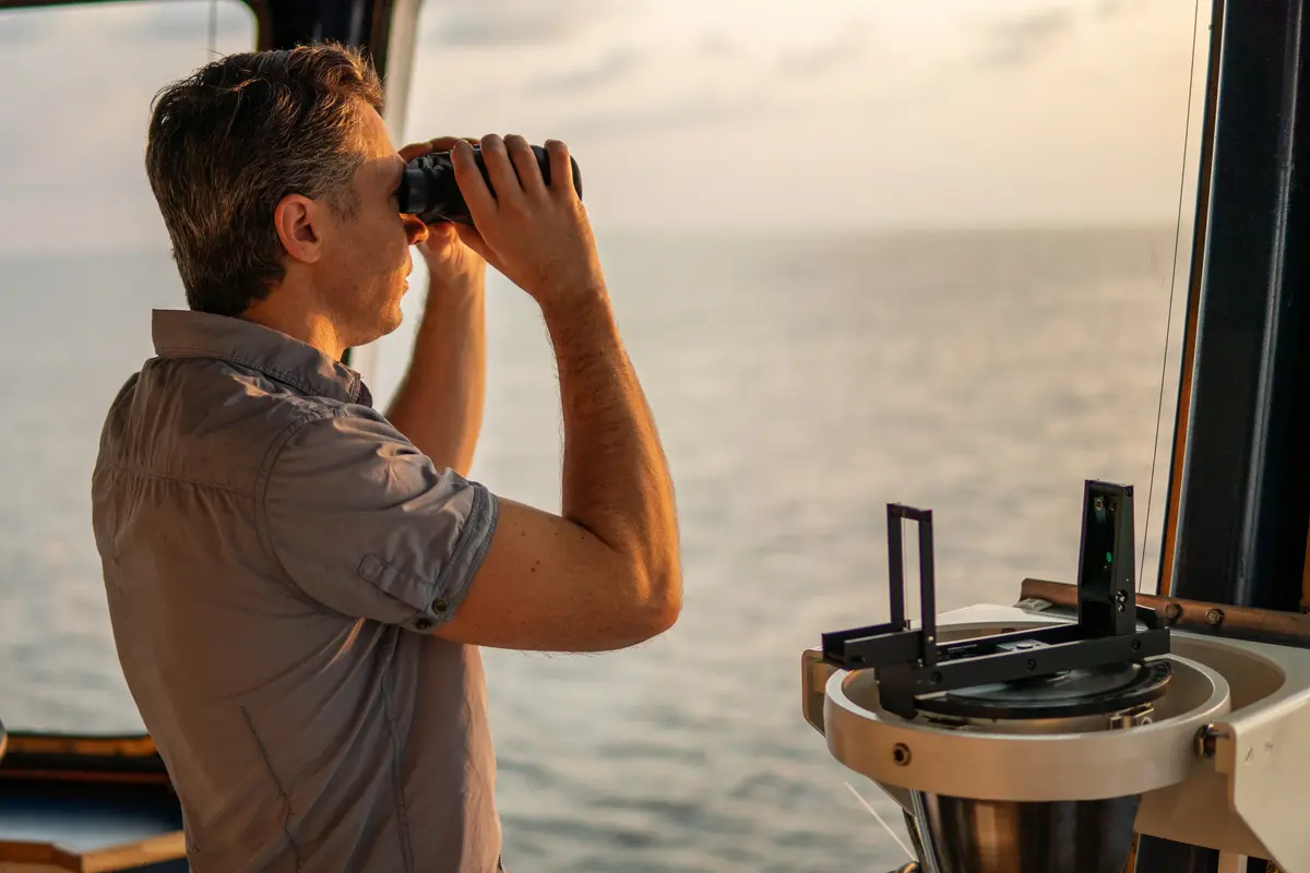 A captain with binoculars looking across the ocean