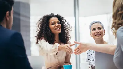 Deux femmes se serrent la main en souriant lors d'une réunion conviviale.