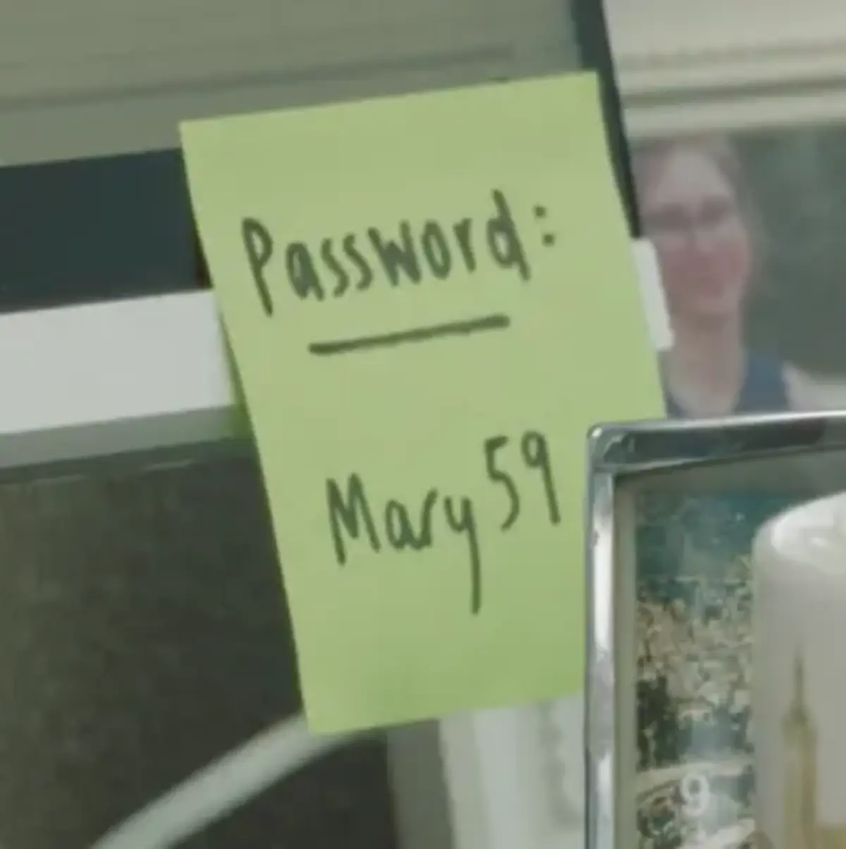 Close-up of a sticky note with "Password: Mary123" written on it, attached to a computer monitor.