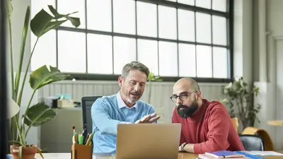 Deux hommes dans un bureau regardent un ordinateur 