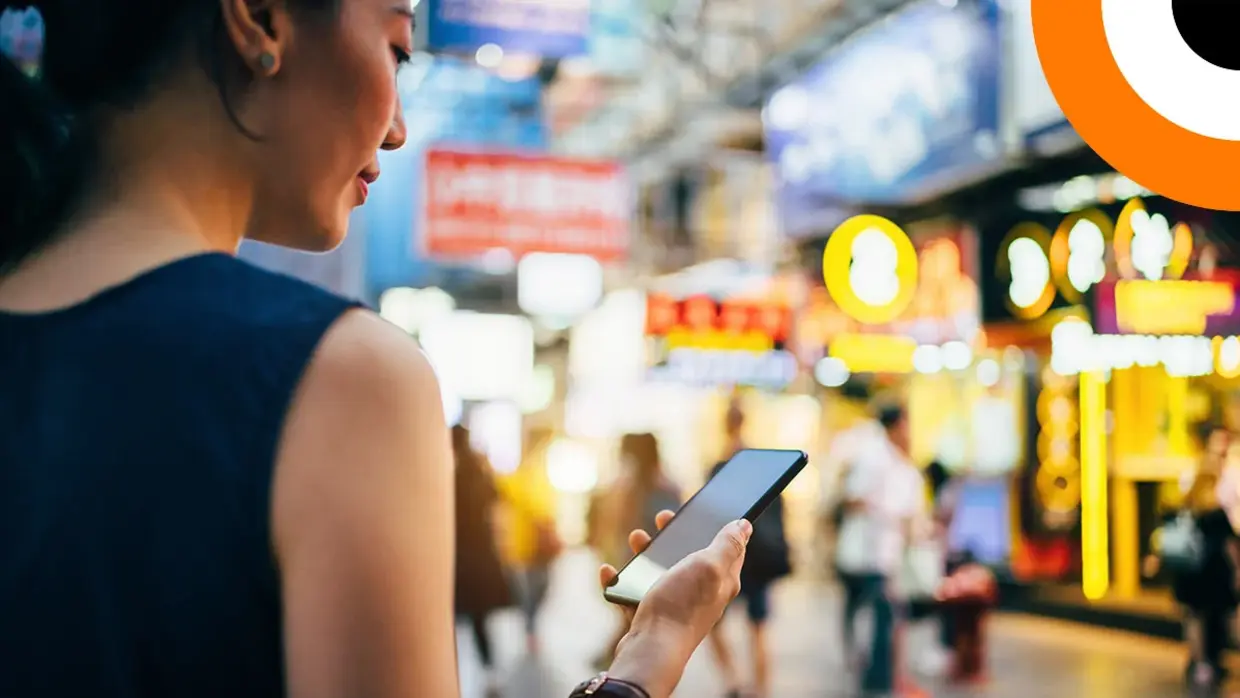 Une jeune femme consulte son smartphone dans la rue. 