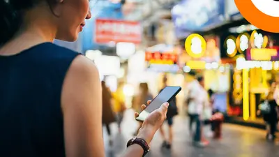 Une jeune femme consulte son smartphone dans la rue. 