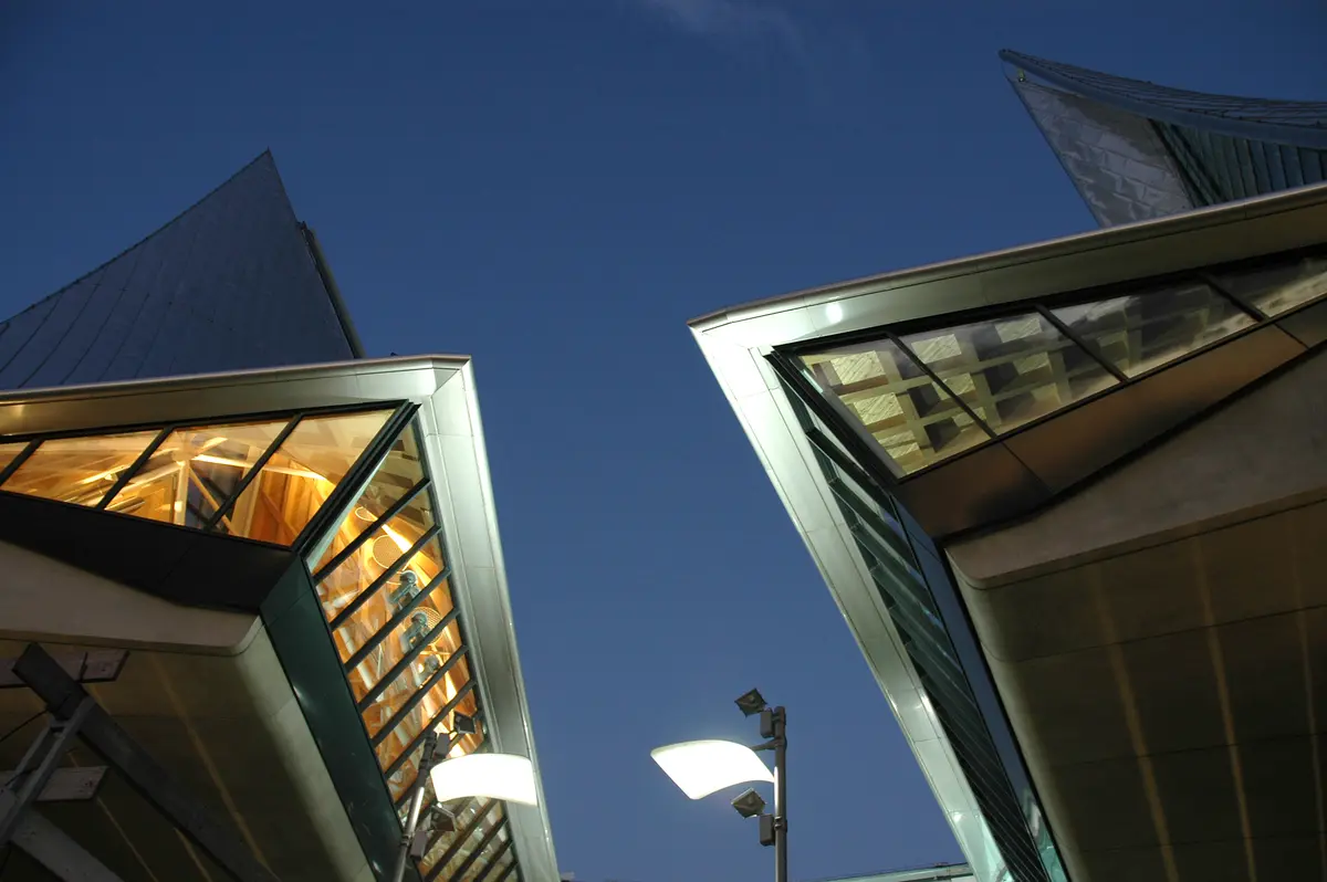 Low-angle shot of a contemporary building with sharp, pointed roof structures against a clear blue sky.