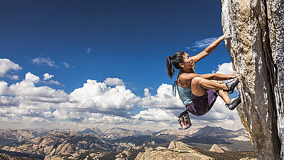 A woman free climbing the side of a cliff