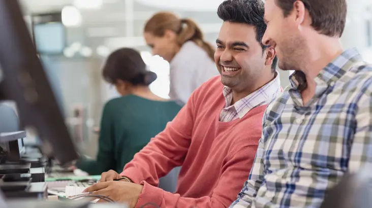 Zwei Männer arbeiten fröhlich am PC