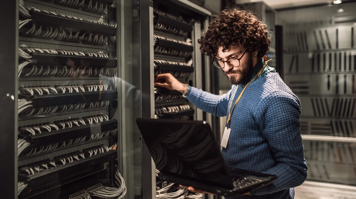 Afbeelding van een man met een laptop bij servers