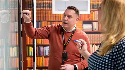 Man explaining a topic to a colleague in the Orange Cyberdefense Stockholm library