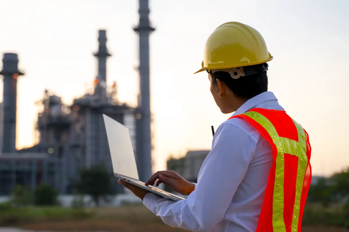Engineer standing with laptop looking at a buiding
