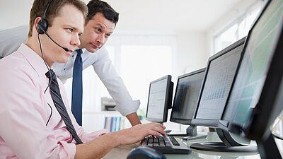 Deux hommes dont un opérateur regardent un écran de surveillance