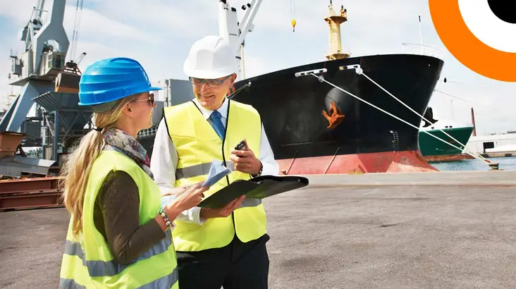 Deux professionnels portant un gilet jaune se consultent l'un l'autre avec en toile de fond un bateau de transport maritime.