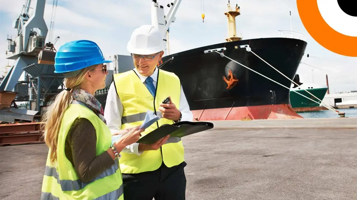 Deux professionnels portant un gilet jaune se consultent l'un l'autre avec en toile de fond un bateau de transport maritime.