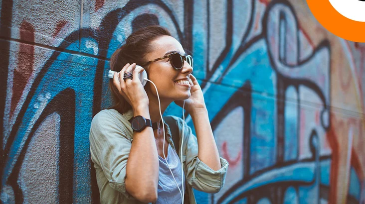 Rap, hip hop et cybersécurité. Une jeune femme écoutant de la musique en souriant, à l'aide d'un casque stéréo.