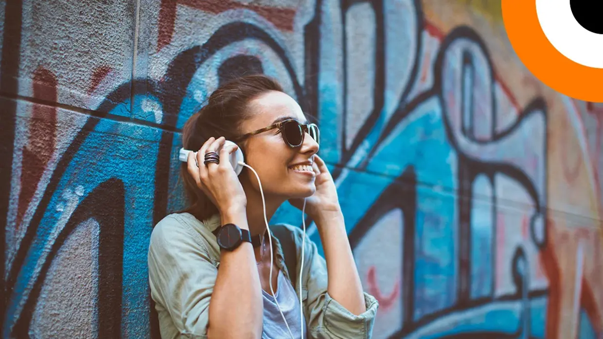 Une jeune femme écoutant de la musique en souriant, à l'aide d'un casque stéréo.