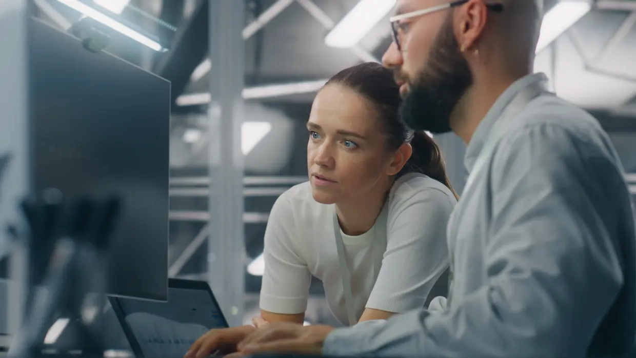 Ein Team aus männlichen und weiblichen IT-Ingenieuren, die gemeinsam vor einem Computerbildschirm wichtige Kennzahlen zur Netzwerkleistung auswerten. Teamarbeit und IT-Überwachung in Echtzeit.