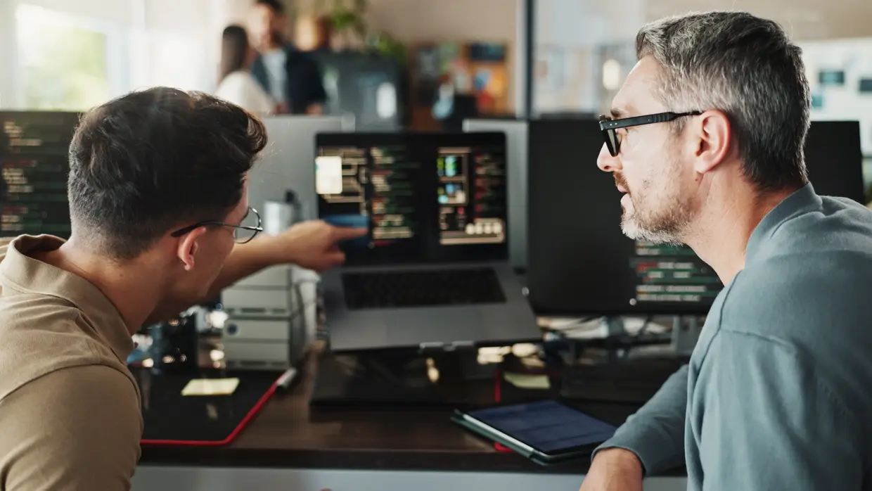 Zwei Männer am Computerbildschirm im Büro testen eine Softwarelösung
