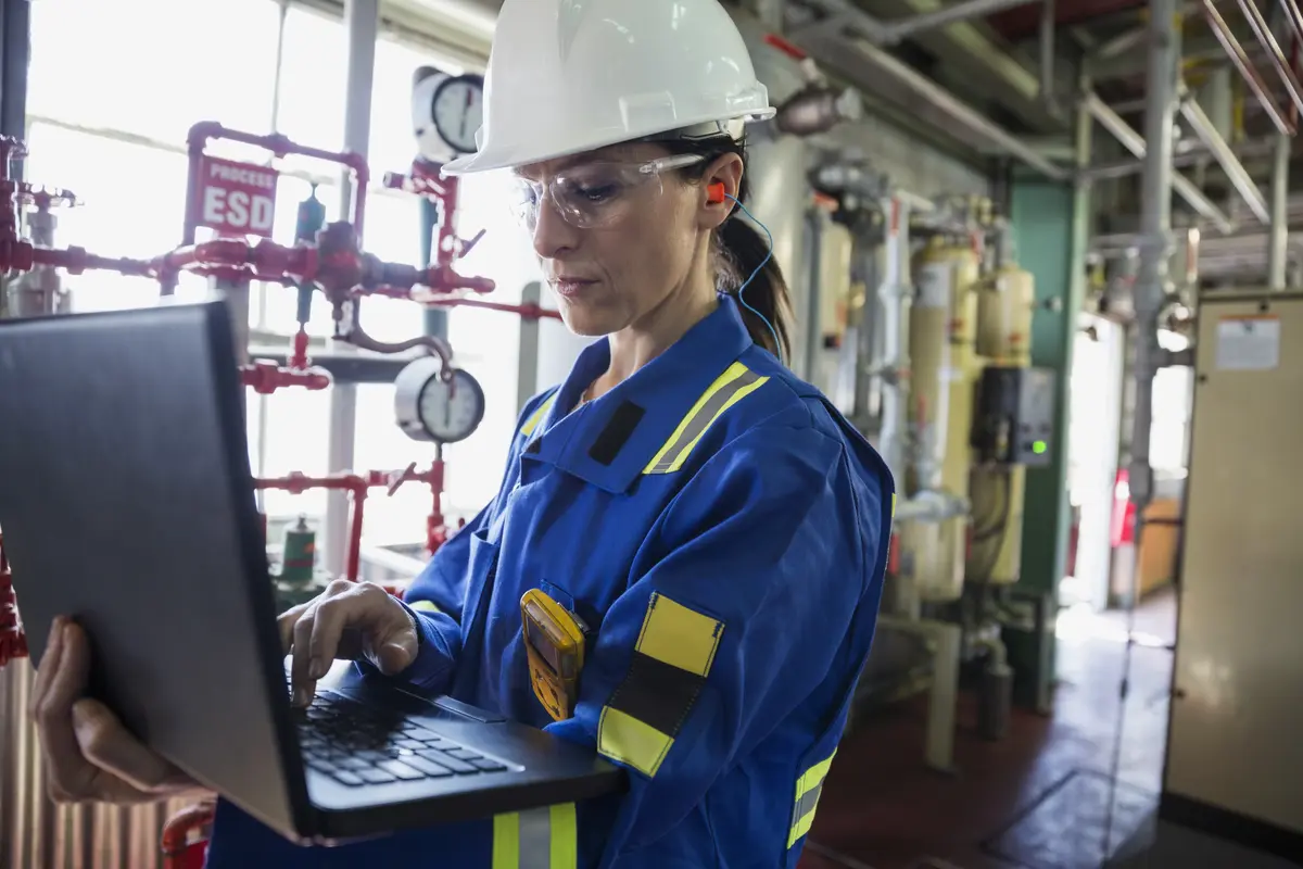 Woman in workwear using a screen in a technical room