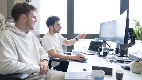 Deux hommes assis avec des ordinateurs en face d'eux.