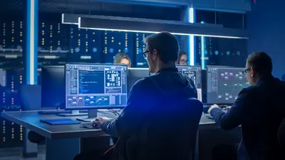  Cybersecurity professionals working in a data center with multiple screens showing code and data.