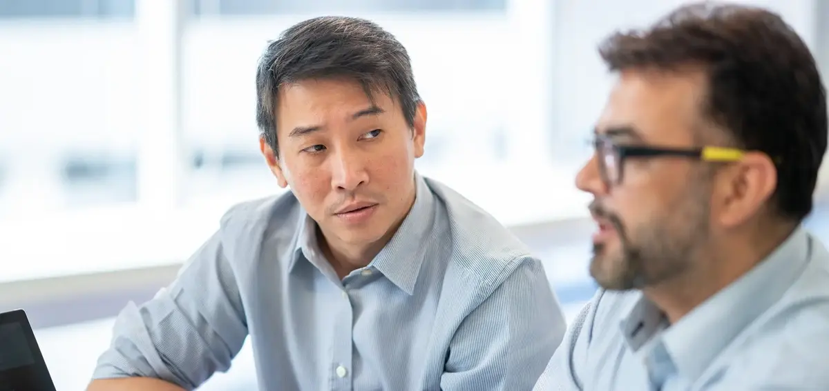 Two team members in discussion will looking at a laptop screen