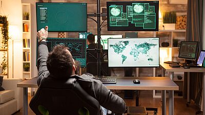 Going well - security professional looking at multiple screens with world data on them