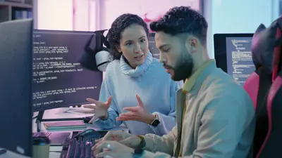 Two developers in from of computer monitors discussion