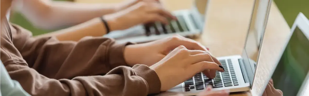 Hände von drei Personen die nebeneinander sitzen und am PC arbeiten