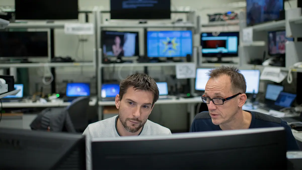 Two men sitting in front of a computer