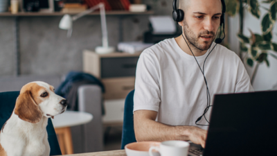 Man with headphones working from home with his dog by his side