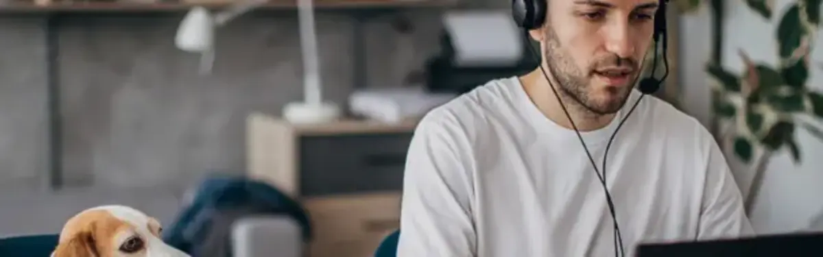 Man with headphones working from home with his dog by his side